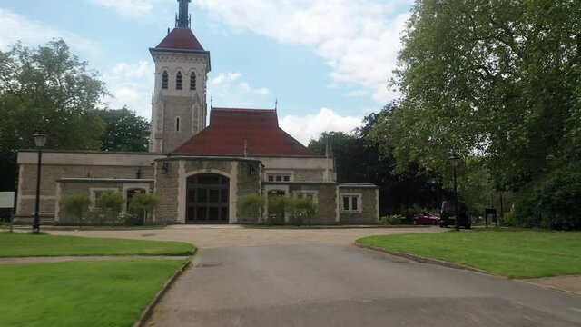 Low altitude flying drone above road in park. Forward tracking funeral car driving around church