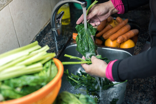 Mujer blanca lavando hojas , zanahoria y otros vegetales desde casa por la cuarentena, con agua limpiando algunas fruta y verdura para eliminar las posibilidades de contaminaci&oacute;n COVID-19,