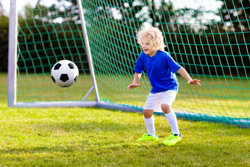 Kids play football. Child at soccer field.