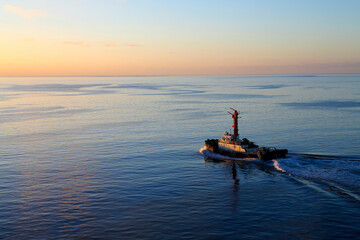 The sun is rising, and a fishing boat in the Pacific Ocean is slowly sailing to the depths of the ocean.