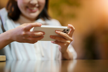 Fototapeta premium 暖かい雰囲気の空間で、スマートフォンの画面を見る若い女性