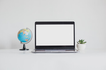 Blank screen laptop between mini globe and succulent isolated on white background