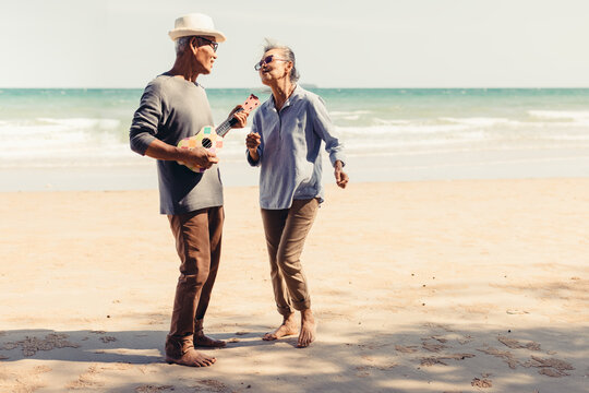 Retired couple Sing and dance happily in the sunlight by the sea. Plan life insurance and retirement concept.