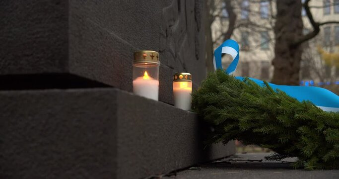 Shot of a couple of candles burning and a green Christmas reef lying next to a stone plaque, Christmas Day