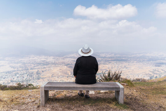 Woman in traditional Mexican ethnic costume. Travel background for Mexico. unrecognizable woman sitting on a bench. looking ahead towards a landscape. travel in Oaxaca, Mexico
