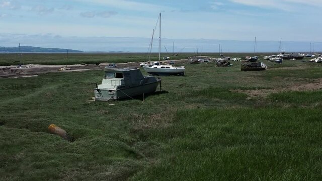 Abandoned old fishing boat carcass shipwreck in shipyard low tide mud flats graveyard low angle push in right