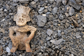 Fototapeta na wymiar Statue of an Aztec warrior made of clay in front of a background of gravel and rocks