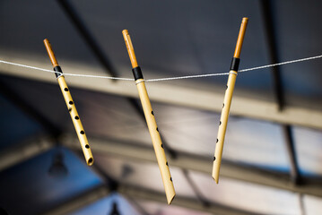 Closeup shot of small bamboo flutes hanging on a string © Hulya Koca/Wirestock
