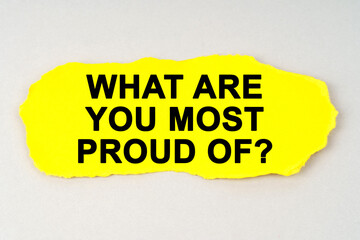 On a white background lies yellow paper with the inscription - WHAT ARE YOU MOST PROUD OF