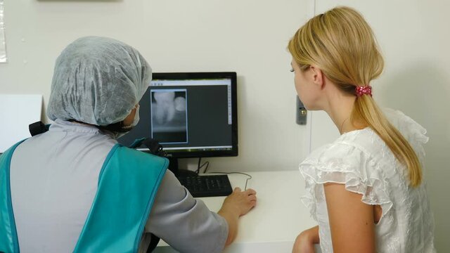 Dentist discusses with female patient plan for recovery and rehabilitation both looking at xray image on monitor screen. doctor looking at x-ray image in private practice. examine xray shot of patient
