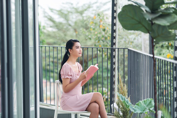 Young woman reads a book at balcony