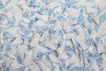 Desiccant silica on the pack background. packet of silica gel buried in silica crystals. There are words desiccant and do not eat on packet