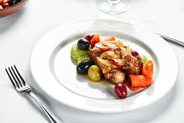 Grilled quail with vegetable stew, light plate table with white tablecloth and cutlery