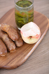 Sausage and a cup of green tea and a bitten peach
