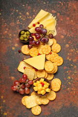 Obraz na płótnie Canvas Tasty crackers with cheese and snacks on grunge background