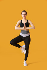 Fototapeta na wymiar Sporty young woman doing yoga on color background