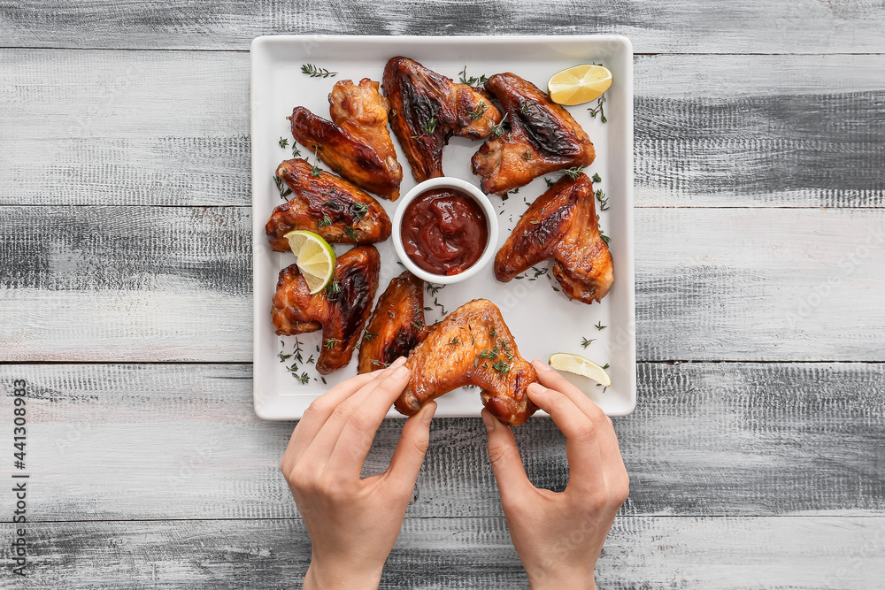 Sticker woman eating roasted chicken wings on wooden background