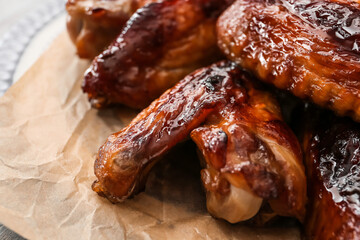 Plate with roasted chicken wings on table