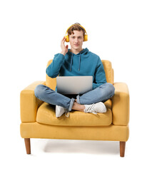 Young man with laptop listening to music while sitting in armchair on white background