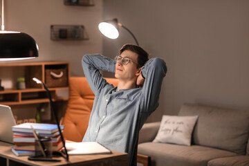 Fototapeta premium Young man resting after studying at home in evening