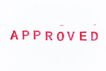 Red color rubber stamp in word approved on white paper background