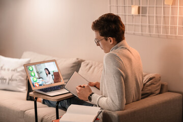 Obraz premium Young man studying online at home in evening