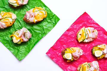 Smorrebrod with various stuffing. Trendy open sandwiches with cream cheese, quail eggs, tomatoes, bacon and vegetables. Modern, summer still life of healthy snacks.  Flat lay in minimalism style. 