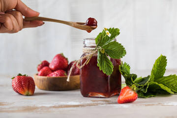 Strawberry jam in a jar, fermented strawberries in a wooden spoon. Fermented berries.