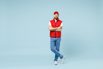 Full size body length professional delivery guy employee man in red cap white T-shirt vest uniform workwear work as dealer courier walk isolated on pastel blue color background studio Service concept - obrazy, fototapety, plakaty
