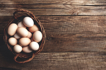 Chicken eggs in basket on wooden background. Organic household