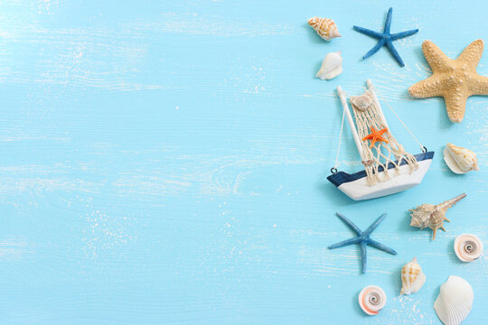 nautical concept with white decorative sail boat, seashells over blue wooden background