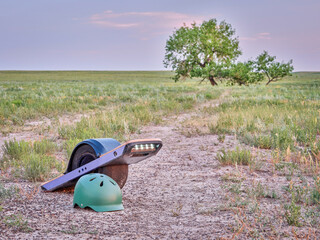 One-wheeled electric skateboard (personal transporter) and helmet on a dirt trail in a prairie