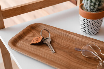 Board with key from house and eyeglasses on shelf, closeup
