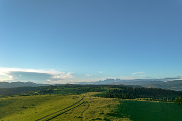 AERIAL: panorama of a forest valley with fields in the mountains. beautiful landscape with clean forest and meadows in early summer