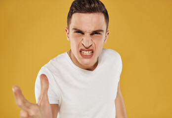 man with angry expression in t-shirt discontent emotion yellow background