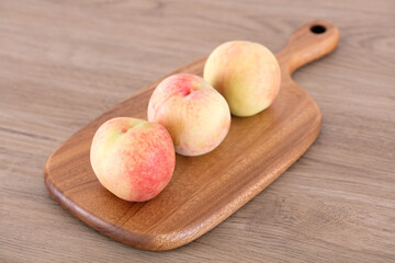 Three peaches on cutting board
