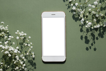 Mobile phone mock up on a pastel green background decorated with white small flowers