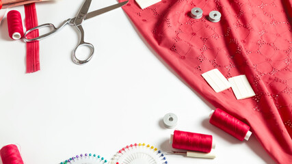 Fashion background. Pattern, fabric, pins, threads and various designer accessories on a white table, top view. Space for text