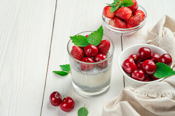 Milk dessert with chia seeds and fresh cherries and strawberries. Creamy pudding on a white background.