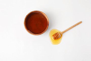 Bowl with sweet honey and dipper on white background