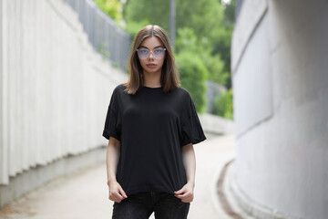Woman or girl wearing black blank cotton t-shirt with space for your logo, mock up or design in casual urban style - obrazy, fototapety, plakaty