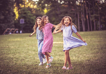 Fototapeta premium Three smiling little girls running trough nature and holding hands.