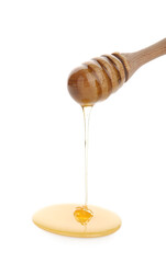Honey pouring from wooden dipper on white background