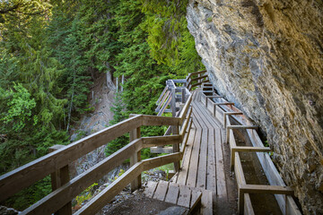 Fototapeta na wymiar Wooden walking trail on cliff following historic irrigation channel Bisse du Ro in canton of Valais