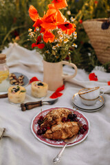 two almond croissants with fresh cherries on a red plate top view. picnic snacks top view. picnic with gourmet desserts outdoors. picnic for two	
