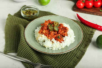 Plate with tasty chili con carne, rice and pickled jalapeno on light background