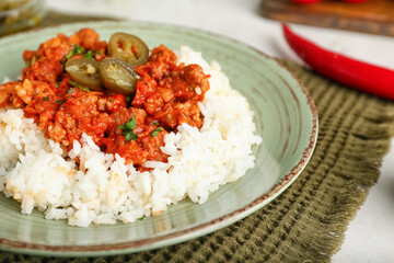 Plate with tasty chili con carne, rice and pickled jalapeno on table, closeup
