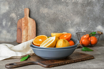 Bowl with healthy citrus fruits on grey background