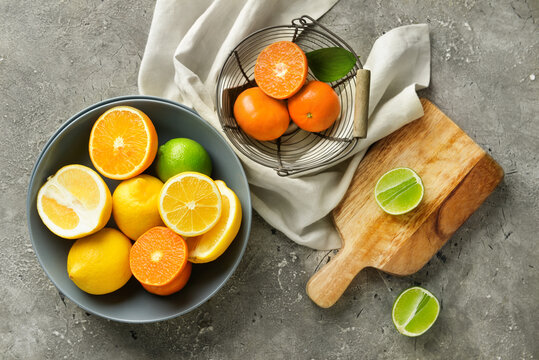 Bowl with healthy citrus fruits on grey background
