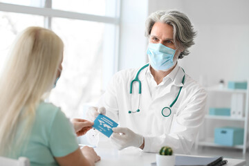 Doctor giving patient her immune passport in clinic